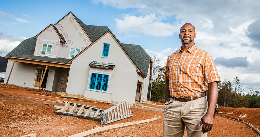 commercial real estate man standing in front of home in construction