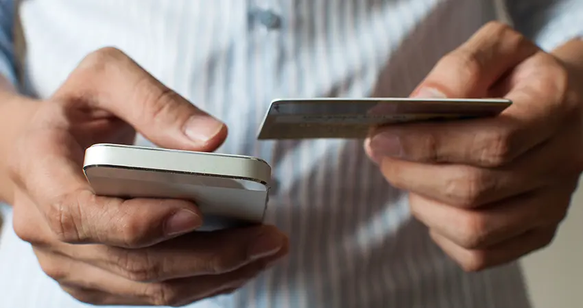 person holding phone and credit card